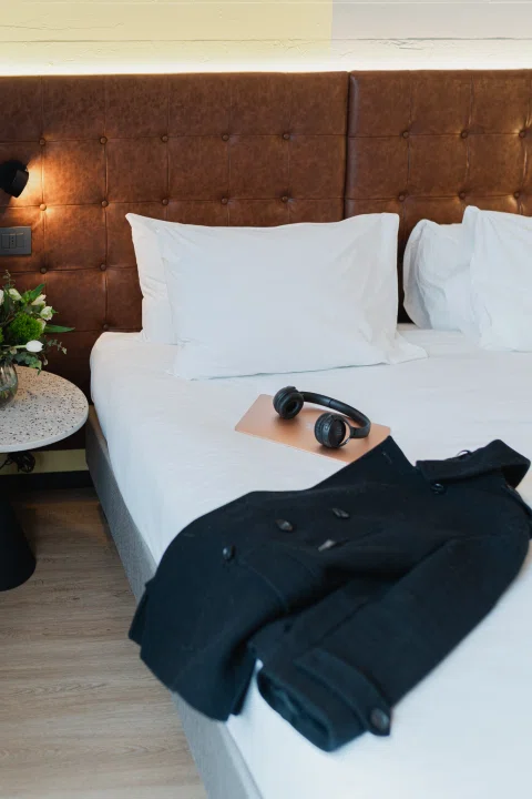 Abrigo negro extendido sobre cama de hotel.