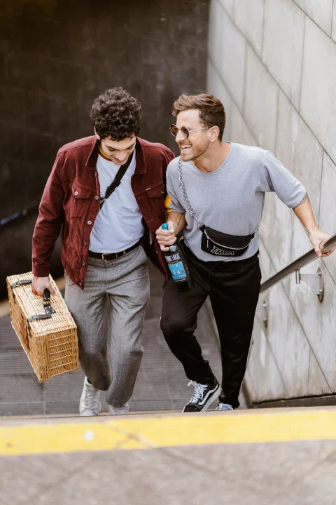 Dos hombres transportan vino en una escena lifestyle urbana.