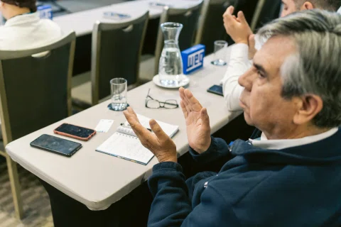 Asistente aplaude sentado durante una sesión de conferencia.