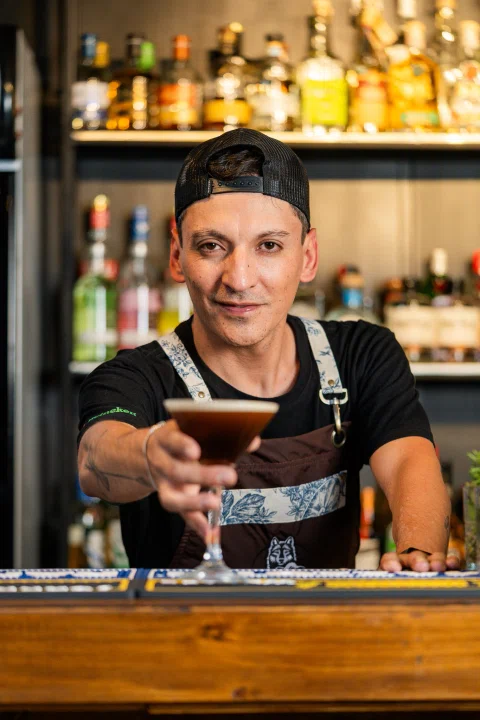 Bartender mostrando una copa detrás de la barra.