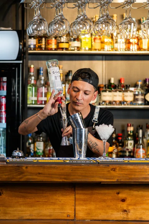 Bartender preparando bebidas detrás de la barra.
