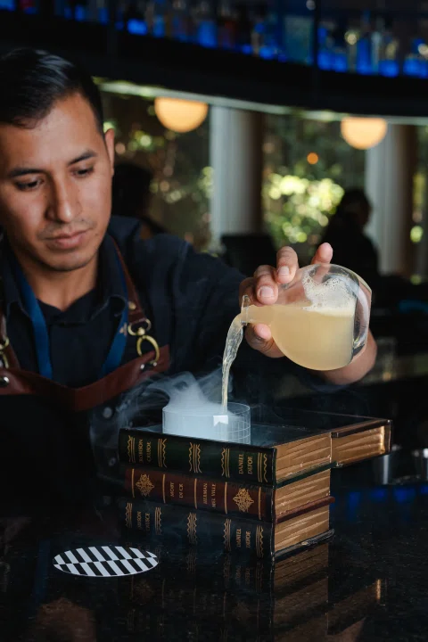 Bartender preparando cóctel con humo en barra.