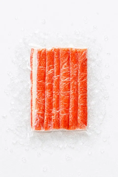 Bastones de surimi alineados sobre hielo.