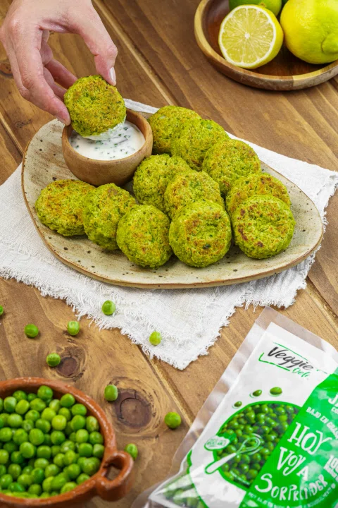 Croquetas de arvejas acompañadas de salsa e ingredientes frescos.