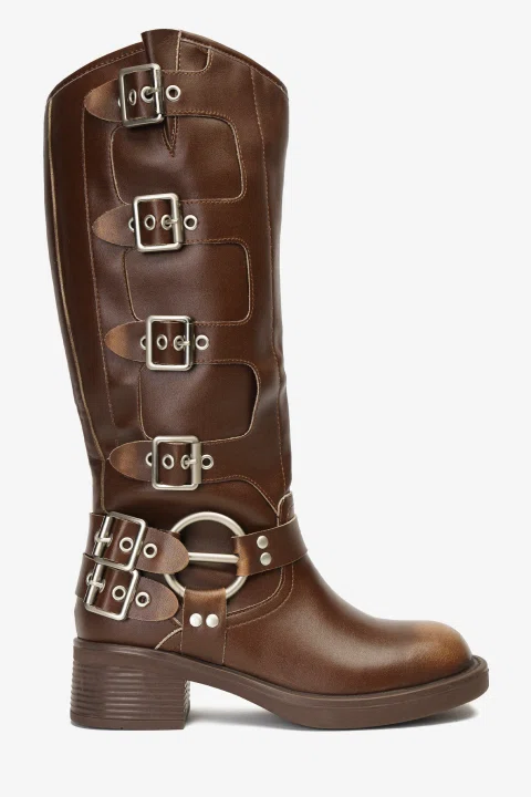 Bota alta de cuero café con hebillas metálicas sobre fondo blanco.