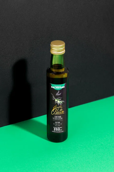 Botella de aceite presentada sobre una composición negra y verde.