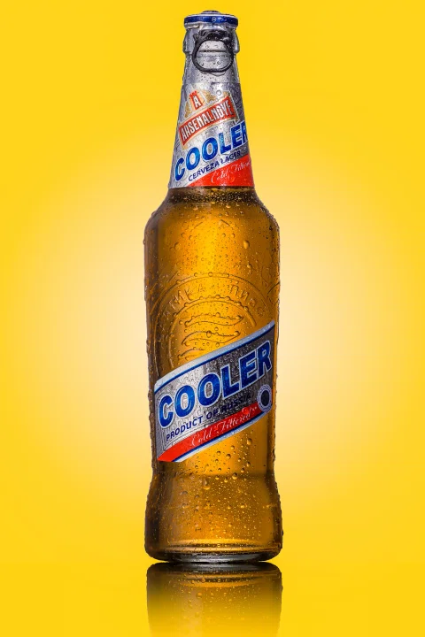 Botella de cerveza presentada sobre fondo amarillo.