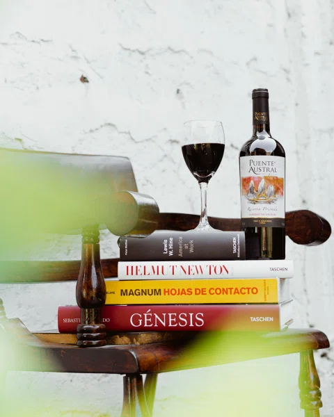 Botella de vino y copas sobre pila de libros.