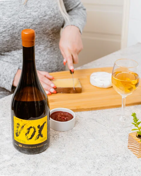 Botella de vino de etiqueta amarilla junto a aperitivo.
