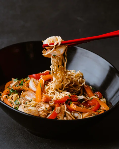 Bowl de noodles con vegetales mientras se levantan fideos.