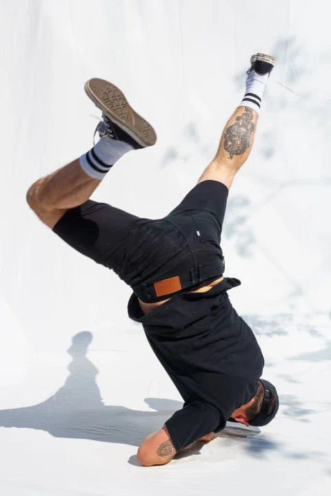 Bailarín de breakdance ejecuta una figura sobre fondo blanco.