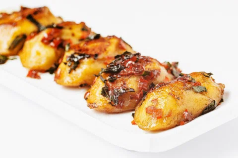 Brochetas glaseadas servidas sobre plato blanco.
