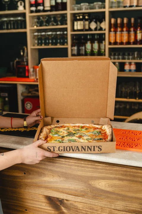 Caja de pizza abierta sobre barra del restaurante.