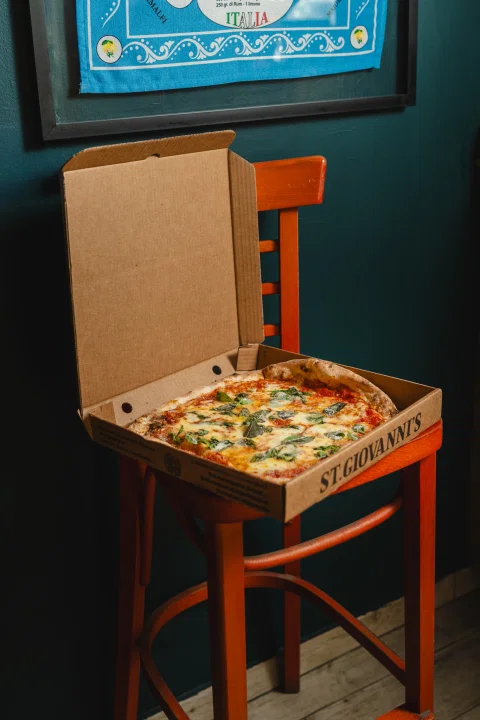 Caja de pizza abierta sobre silla roja.