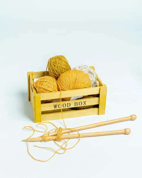 Cajón amarillo con ovillos y agujas.
