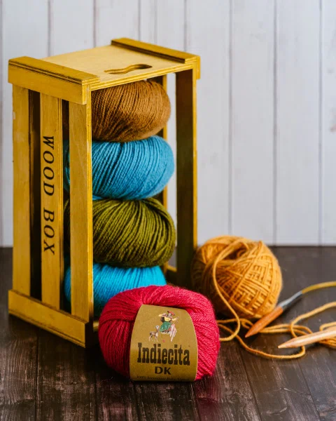 Cajón amarillo vertical con ovillos de colores.