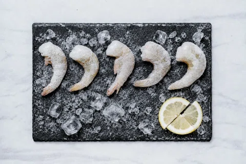 Camarones grandes empanizados alineados con limón.