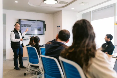 Capacitación interna con instructor y participantes en una sala de reunión.