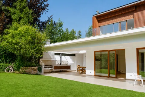 Casa moderna con terraza cubierta y jardín.
