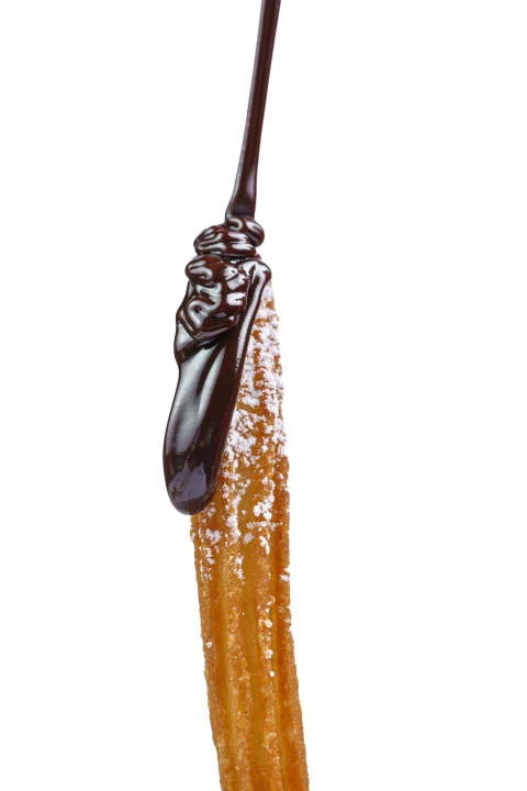 Churro cubierto con chocolate derretido sobre fondo blanco.