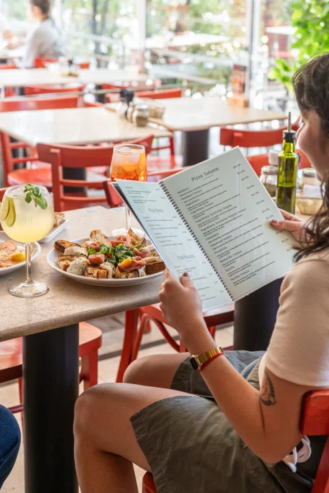 Cliente leyendo menú en mesa exterior.