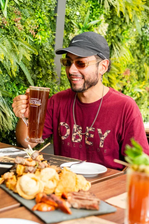 Cliente en terraza con cerveza y tabla de comida.