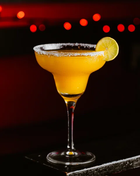 Cóctel amarillo con borde de sal y limón.