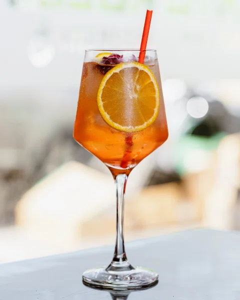 Cóctel naranja con rodaja de limón.