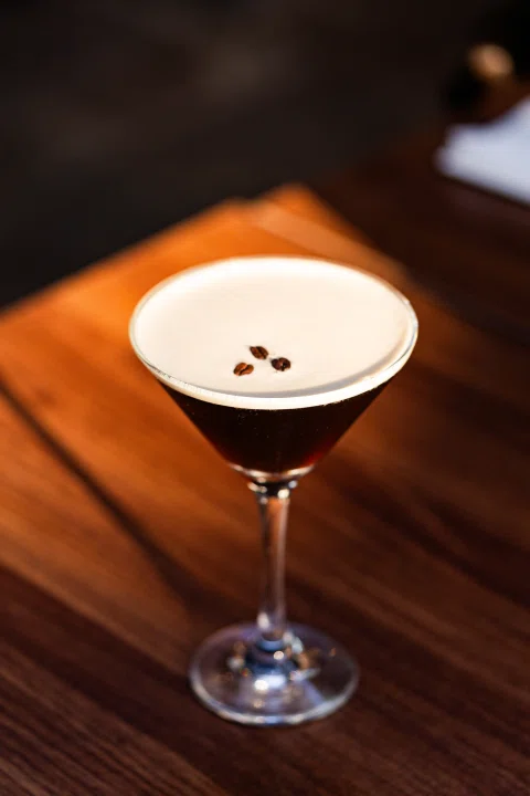 Cóctel tipo espresso con espuma y granos de café.