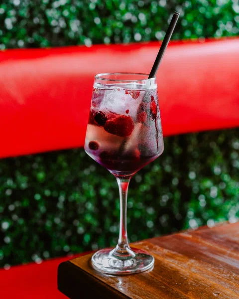 Cóctel rojo con hielo servido en terraza.