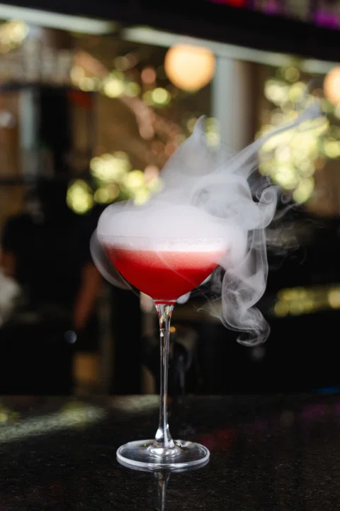 Cóctel rojo con humo sobre barra del hotel.