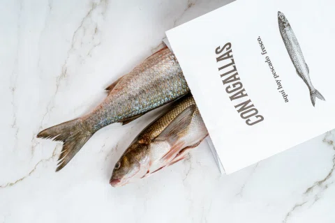 Colas de pescado junto a tarjeta de Con Agallas.