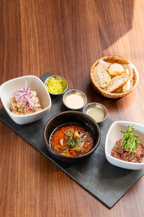 Conjunto de platos salsas y pan sobre mesa.