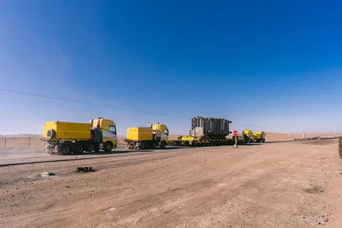 Convoy de transporte industrial estacionado en desierto.