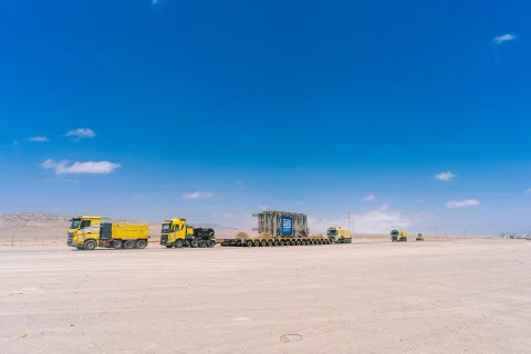 Convoy de transporte industrial en salar bajo cielo azul.