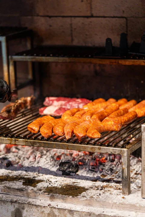Cortes de carne asándose sobre parrilla.