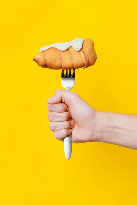 Croissant sobre un tenedor en una composición de fondo amarillo.