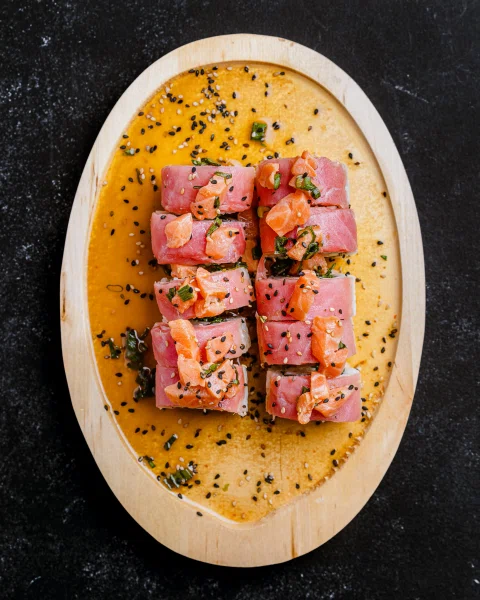 Cubos de salmón sobre salsa naranja.