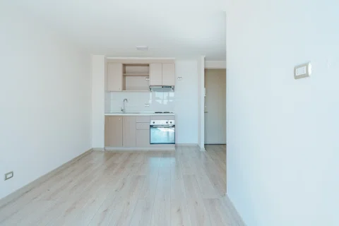 Departamento vacío con cocina integrada y terminaciones en tonos claros.