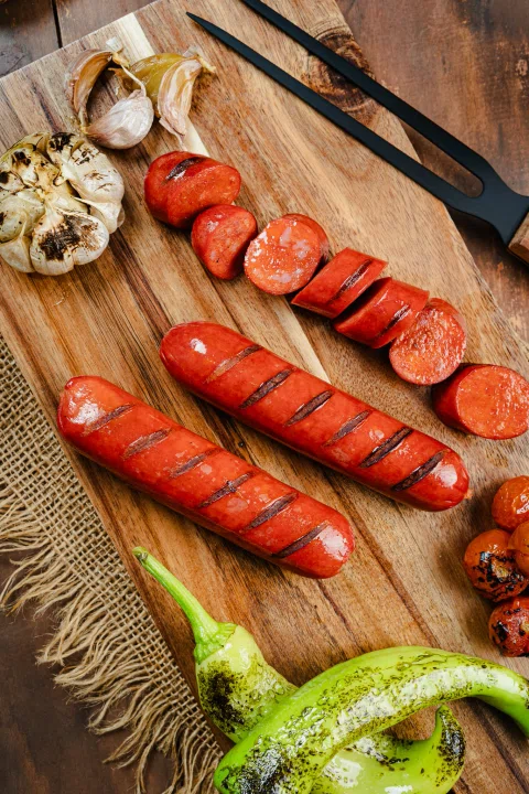 Detalle de salchichas vegetales rojas sobre tabla.
