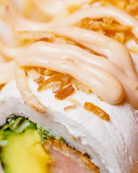 Detalle de sushi con salsa cremosa y palta.