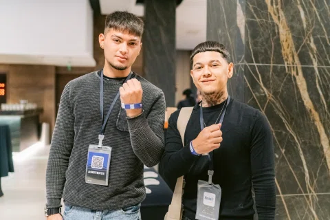 Dos asistentes posan con credenciales durante el encuentro.