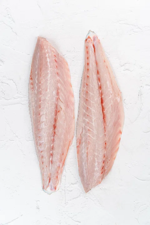 Dos filetes de pescado rosado sobre fondo blanco.