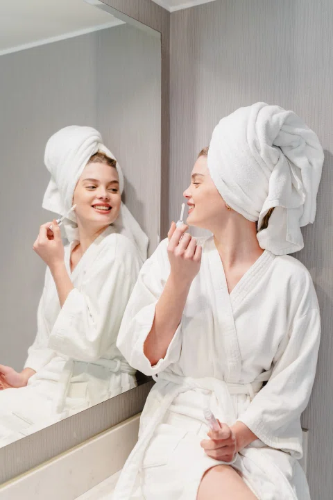 Dos mujeres con batas frente a espejo del baño.
