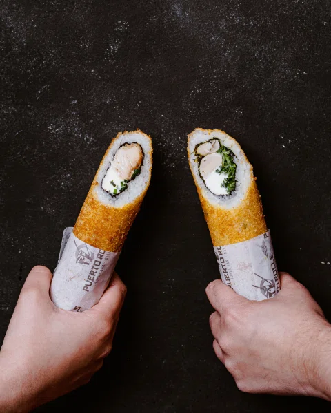 Dos personas sosteniendo rolls tipo burrito.