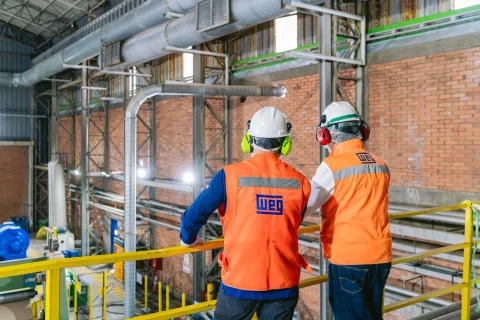 Dos técnicos caminando por pasarela de planta.