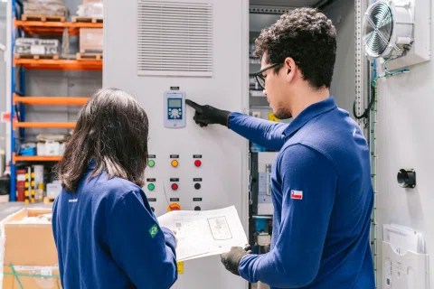 Dos técnicos revisando tablero eléctrico abierto.
