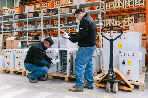 Dos técnicos trabajando en gabinetes montados sobre pallets.