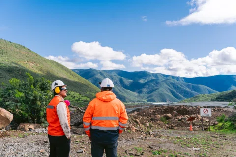 Dos trabajadores observando paisaje de faena minera.