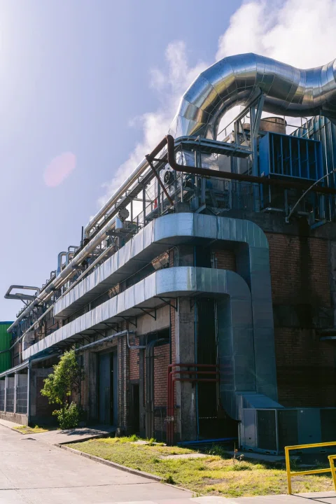 Edificio industrial con grandes ductos y conducciones metálicas exteriores.